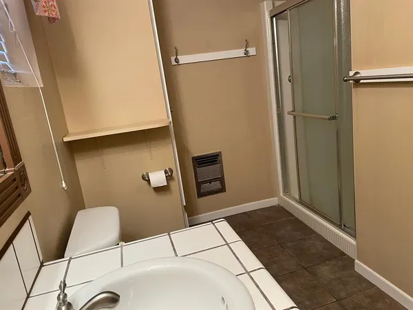 a bathroom with a sink a toilet a mirror and shower