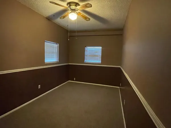 an empty room with a ceiling fan and carpet