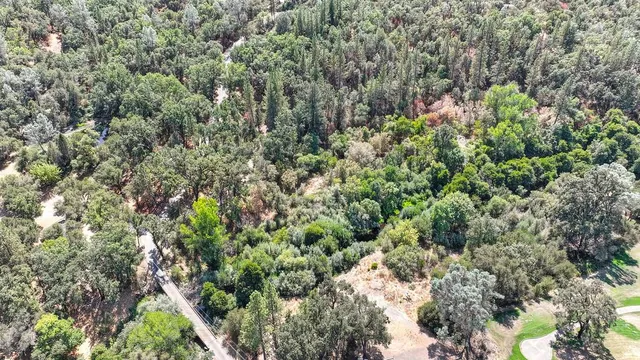 an aerial view of house with outdoor space and trees all around