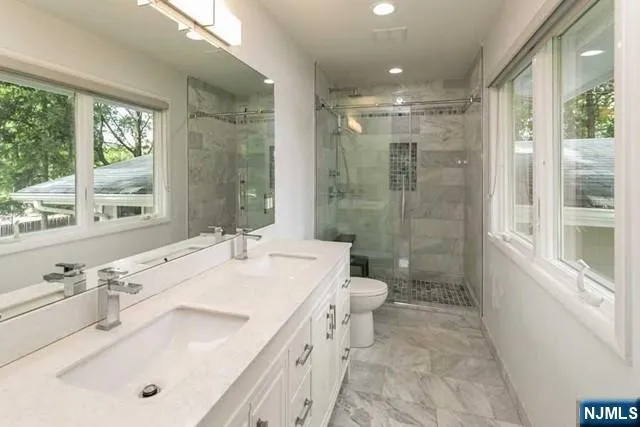 a bathroom with a sink a toilet a large mirror and shower