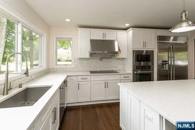 a kitchen with stainless steel appliances kitchen island granite countertop a refrigerator and a sink