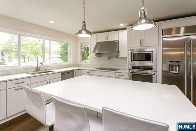 a large kitchen with kitchen island a large counter top appliances and cabinets