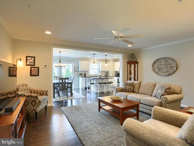 a living room with furniture kitchen view and a wooden floor