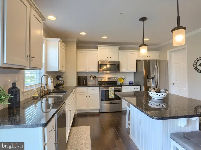 a kitchen with stainless steel appliances granite countertop a sink refrigerator stove and microwave