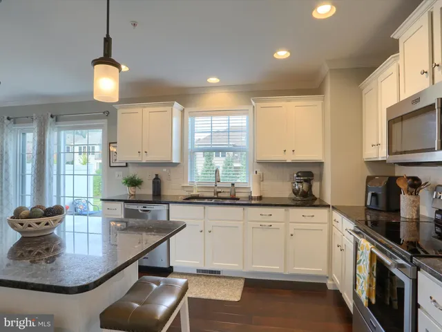 a kitchen with stainless steel appliances granite countertop a sink a stove and a wooden floors
