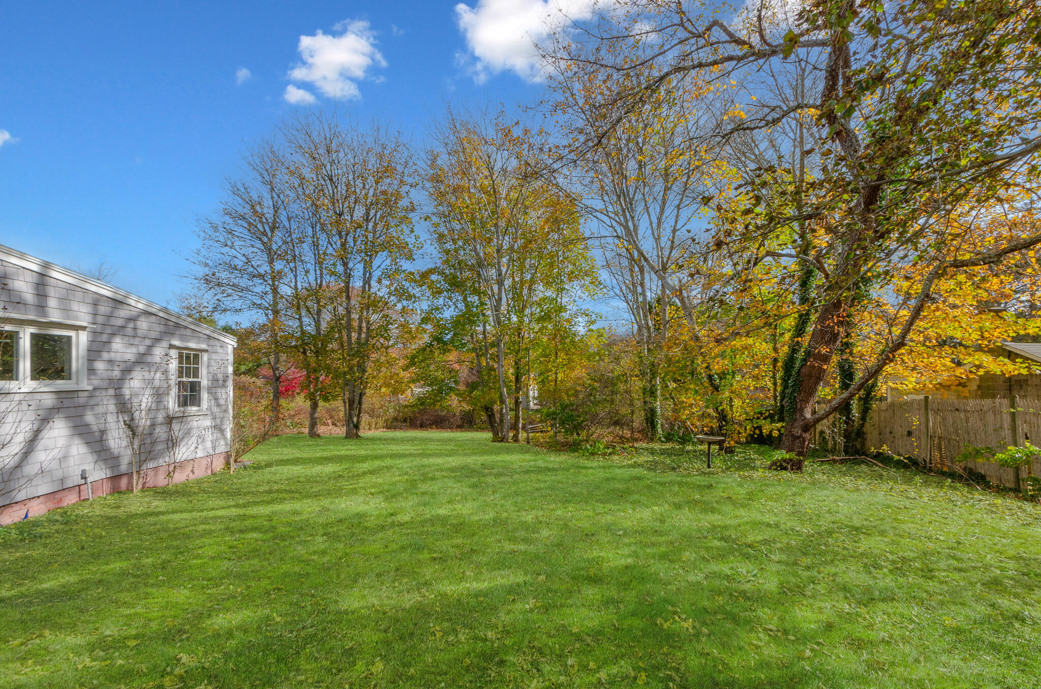 9 Mansion Street West Harwich, MA 02671 - Photo 21 of 26 a backyard of a house with plants and large trees
