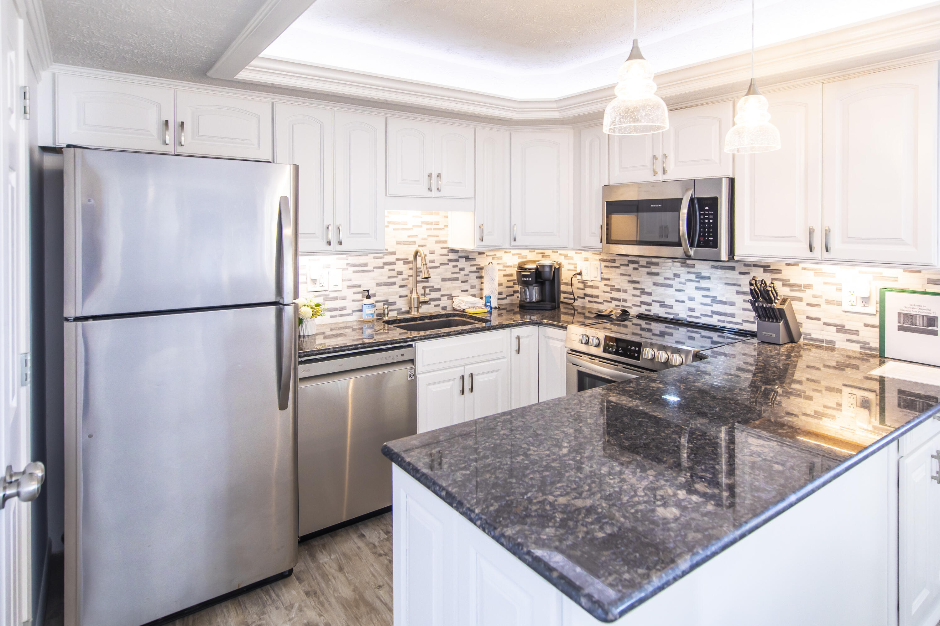 23223 Front Beach Road, Unit A122 Panama City Beach, FL 32413 - Photo 9 of 45 a kitchen with stainless steel appliances granite countertop a refrigerator stove microwave and sink