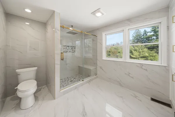 a bathroom with a shower a toilet and a window