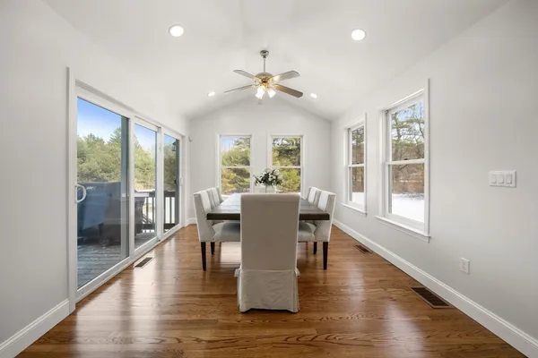 a dining room with wooden floor a chandelier a glass table and windows