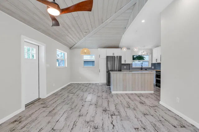 a room with stainless steel appliances kitchen island wooden floors and white walls