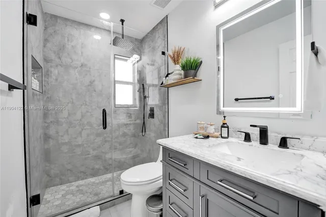 a bathroom with a granite countertop sink mirror vanity and toilet