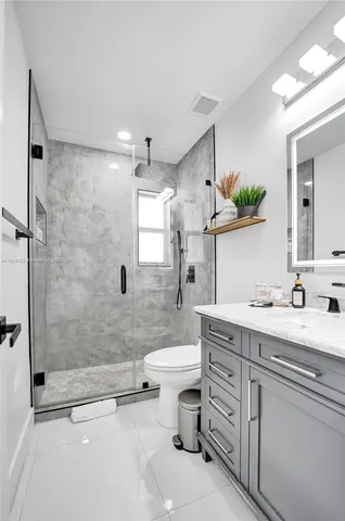 a bathroom with a granite countertop sink a mirror and a shower