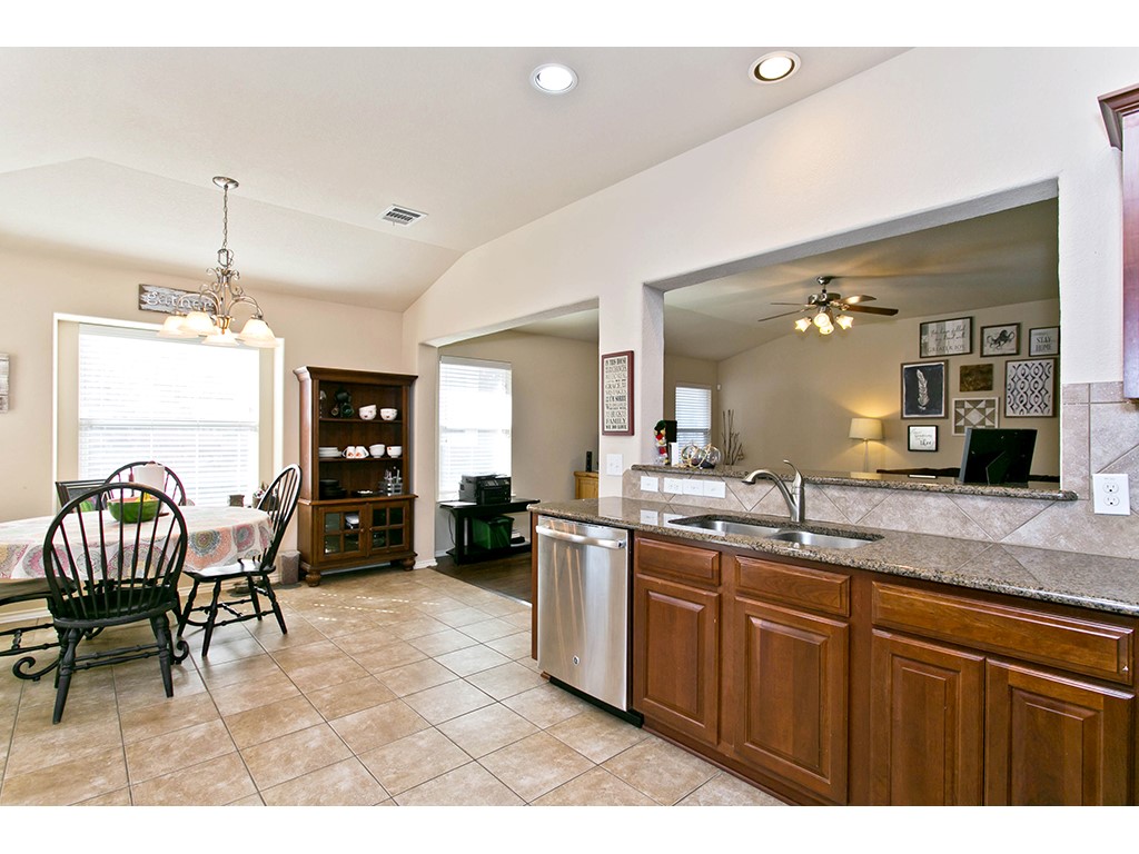 1808 Sand Creek Road Cedar Park, TX 78613 - Photo 5 of 25 Kitchen featuring granite countertops, wood cabinetry, stainless steel dishwasher, and tiled flooring