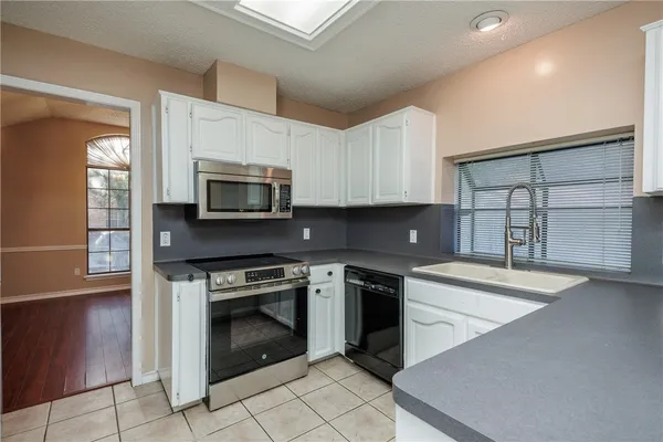 a kitchen with granite countertop a stove top oven microwave and cabinets