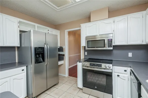 a kitchen with stainless steel appliances granite countertop a refrigerator stove and white cabinets