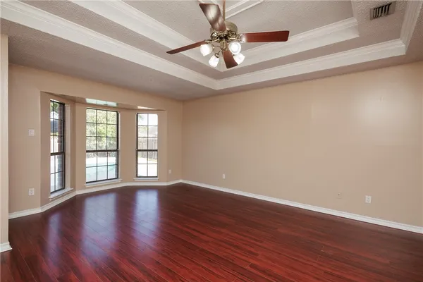 a view of an empty room with window and wooden floor