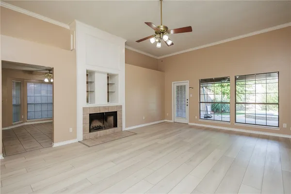 a view of an empty room with wooden floor fireplace and a window