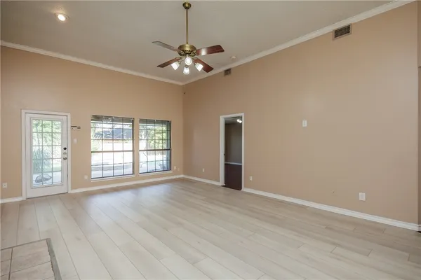 a view of an empty room with wooden floor and a window