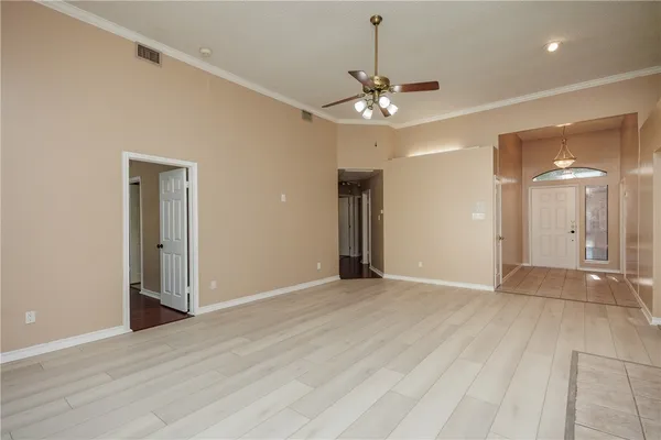 an empty room with wooden floor and ceiling fan