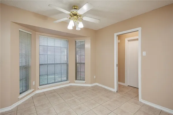 an empty room with chandelier fan and windows
