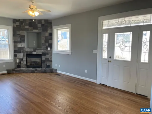 an empty room with wooden floor fireplace and windows