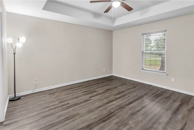 an empty room with wooden floor chandelier fan and windows