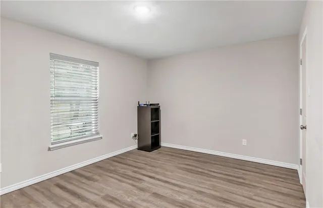 a view of an empty room with wooden floor and a window