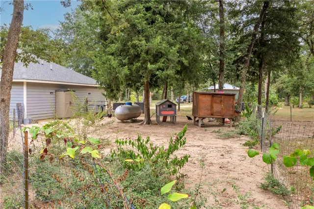 a view of a backyard with table and chairs potted plants and large tree