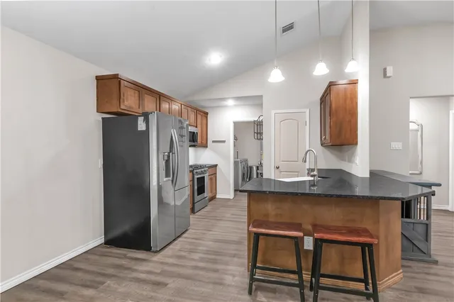a kitchen with stainless steel appliances a refrigerator and a wooden cabinets