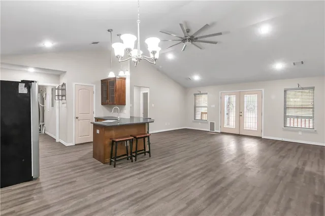 a view of an empty room with wooden floor and a kitchen