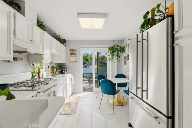 a kitchen with stainless steel appliances kitchen island granite countertop a refrigerator a stove a sink dishwasher and white cabinets with wooden floor