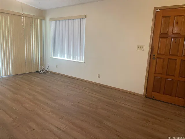 an empty room with wooden floor cabinet and windows