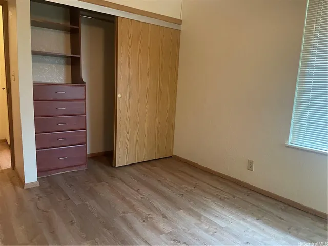 a view of an empty room with closet and a window