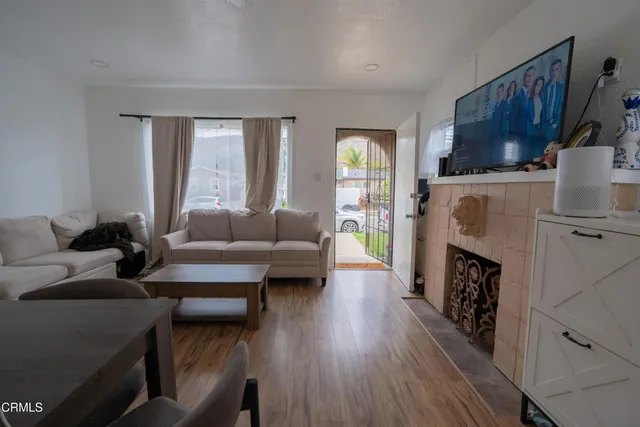 a living room with furniture a fireplace a flat screen tv and a large window