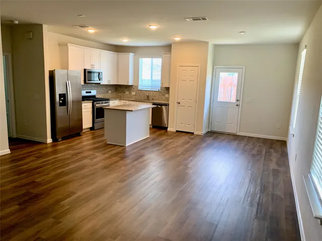 a kitchen with granite countertop a refrigerator and wooden floors
