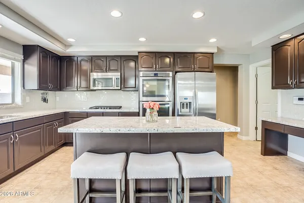 a kitchen with stainless steel appliances granite countertop a dining table chairs sink and cabinets