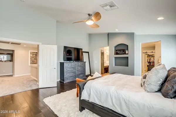 a spacious bedroom with a bed and a flat screen tv