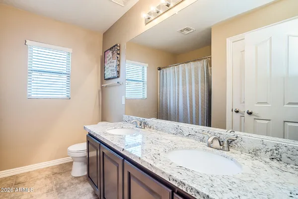 a bathroom with a granite countertop sink toilet and large mirror