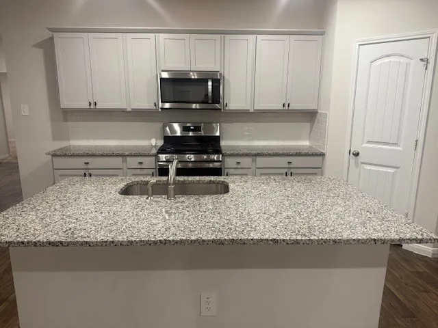 a kitchen with a sink a stove and a microwave