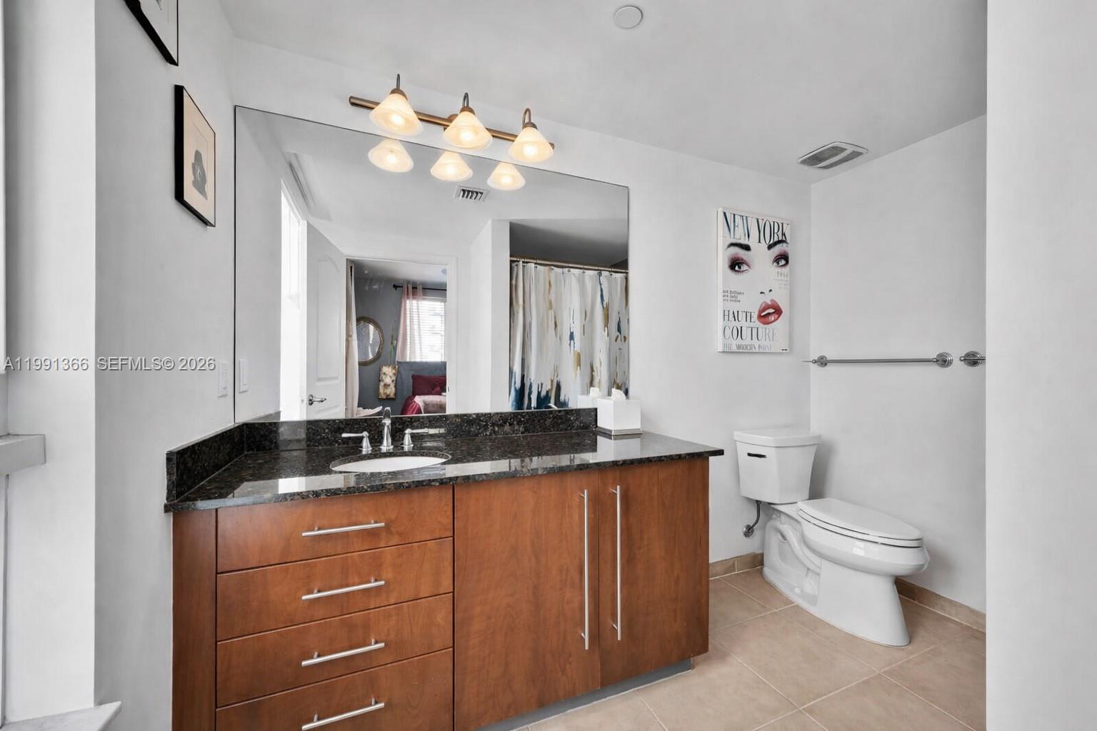 7350 Southwest 89th Street, Unit 1511S Miami, FL 33156 - Photo 11 of 29 a bathroom with a granite countertop sink a toilet and a mirror