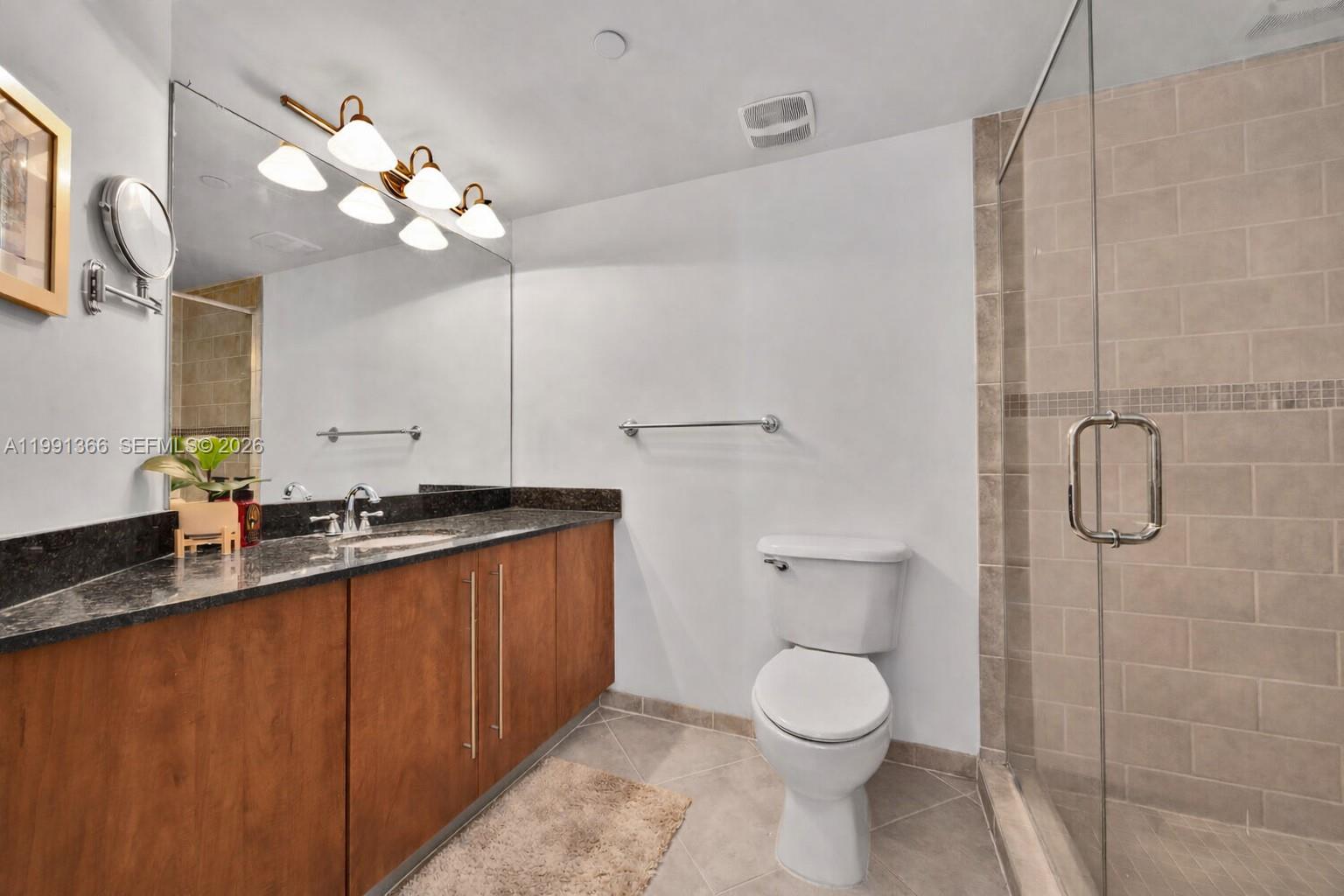 7350 Southwest 89th Street, Unit 1511S Miami, FL 33156 - Photo 14 of 29 a bathroom with a granite countertop sink a toilet a mirror and shower