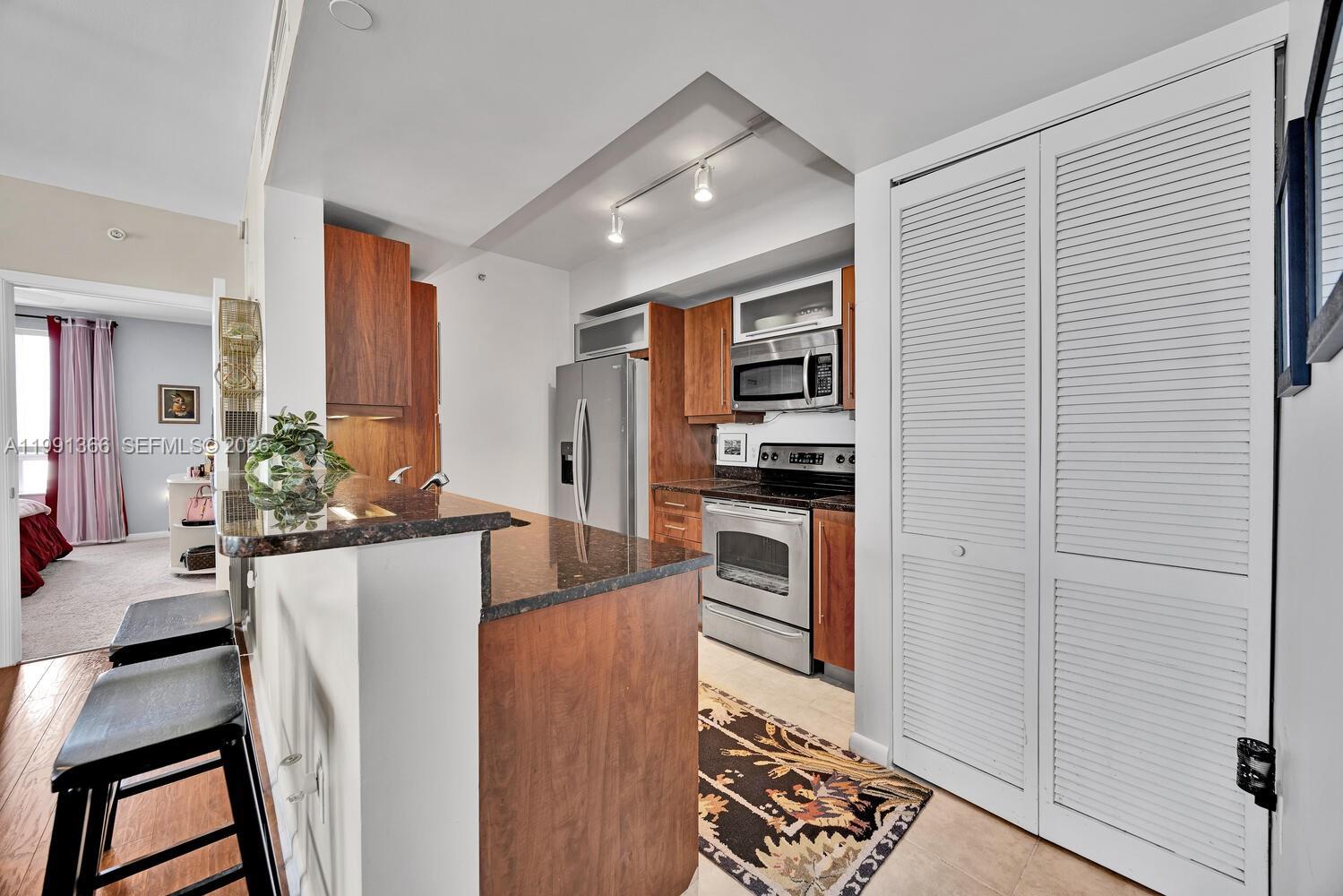7350 Southwest 89th Street, Unit 1511S Miami, FL 33156 - Photo 7 of 29 a kitchen with stainless steel appliances kitchen island granite countertop a refrigerator and a stove top oven