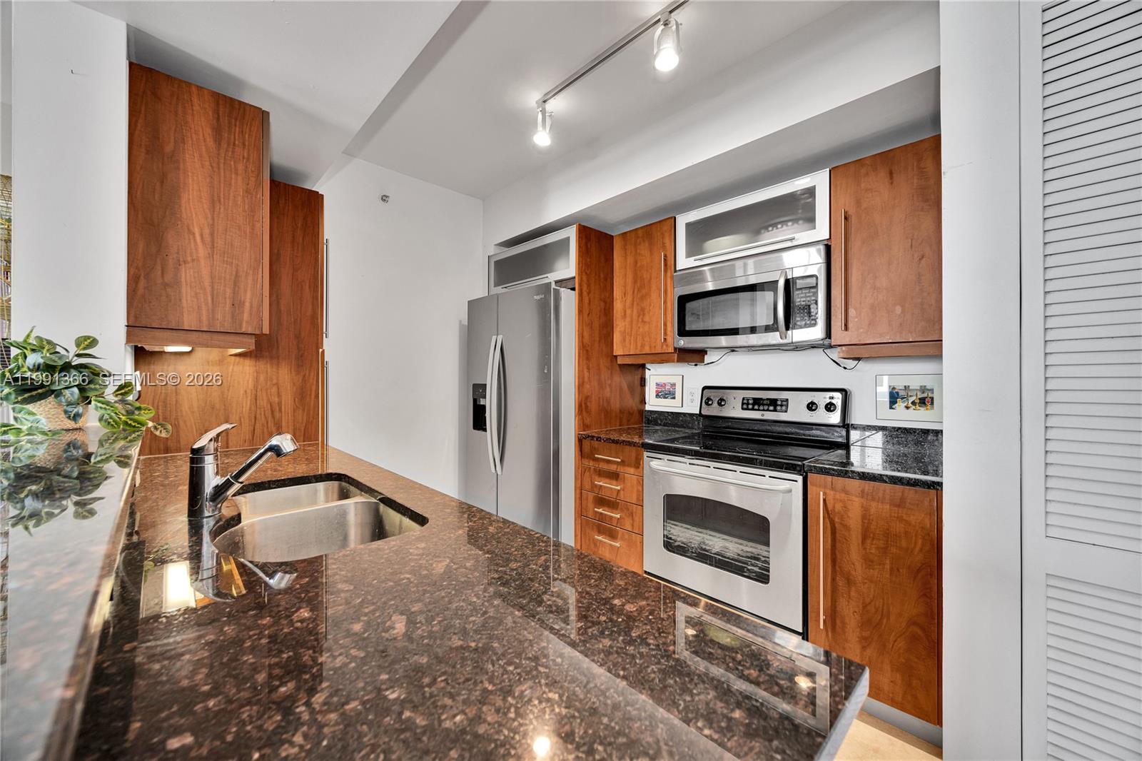 7350 Southwest 89th Street, Unit 1511S Miami, FL 33156 - Photo 8 of 29 a kitchen with stainless steel appliances granite countertop a sink a stove and a refrigerator