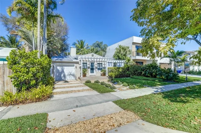 a view of a garden with a bench in front of the house