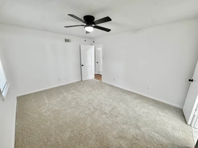 an empty room with a ceiling fan and window