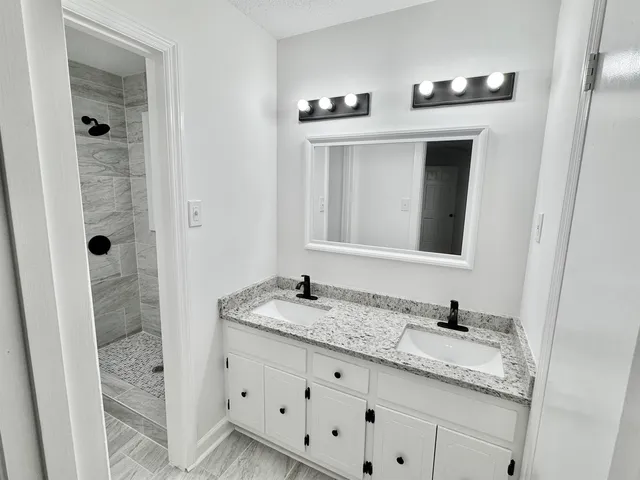 a bathroom with a granite countertop sink and a mirror
