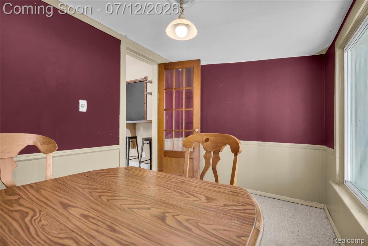 624 North Prospect Road Ypsilanti, MI 48198 - Photo 18 of 28 Dining area featuring a wood-panel door with glass inserts, a large window, a ceiling-mounted light fixture, and two-tone wall finishes