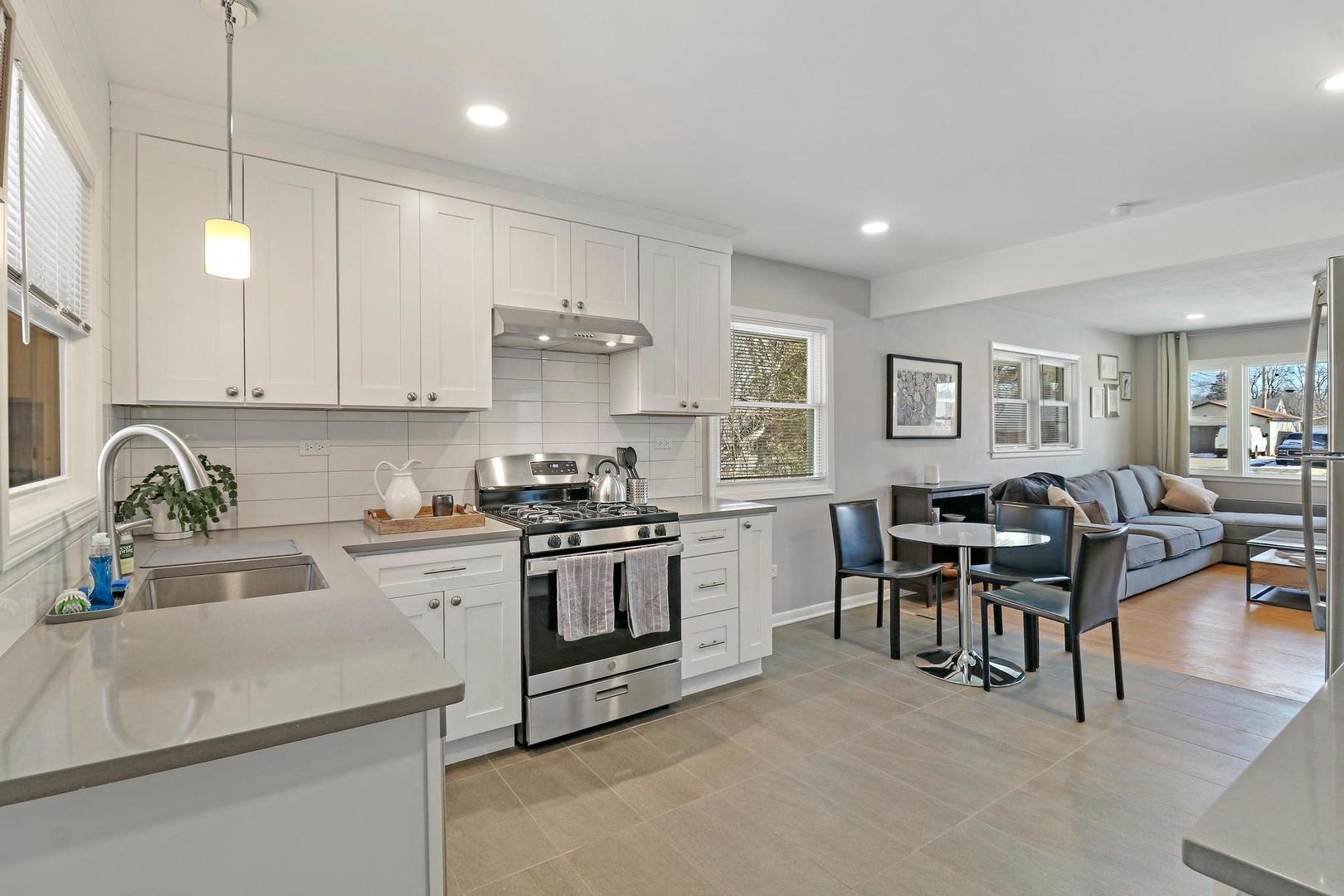 2532 North Jackson Street Waukegan, IL 60087 - Photo 11 of 29 a kitchen with stainless steel appliances granite countertop a stove top oven a sink a dining table and chairs with white cabinets