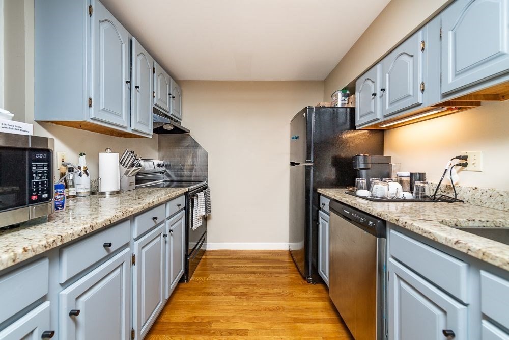 a kitchen with stainless steel appliances granite countertop a sink and dishwasher a stove top oven with wooden floor