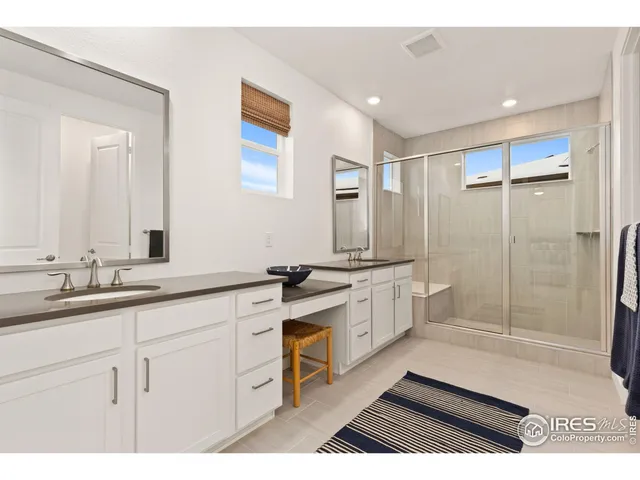 a spacious bathroom with a shower a sink and a mirror